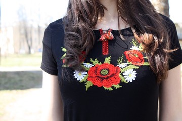 Young slim girl with brunette long hair wearing national theme t-shirt with red flowers poppies, old style embroidery close up