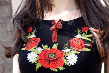 Young slim girl with brunette long hair wearing national theme t-shirt with red flowers poppies, old style embroidery close up