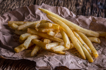 Potato fries. Gold potato fries with salt and dry herbs on wooden board.