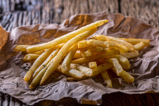Potato fries. Gold potato fries with salt and dry herbs on wooden board.