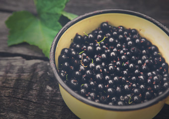 Black currants pot closeup on rustic wood background
