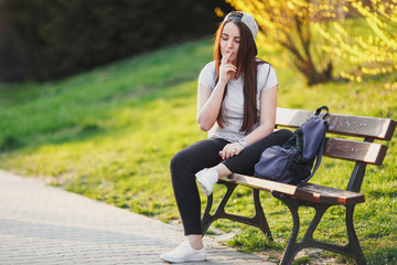 Young girl smoke cigarette at park with sunset