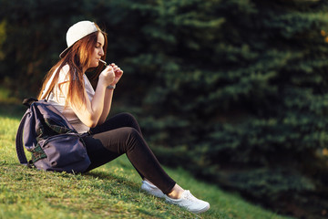Young girl smoke cigarette at park with sunset