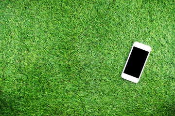 Education concept, Mobile phone with equipment and supplies for work on grass background.