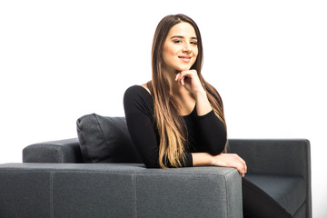 Portrait of happy young woman sitting on sofa on white background