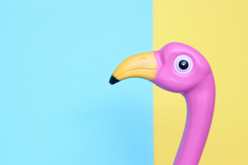 Pink plastic flamingo on pastel background with room for copy.