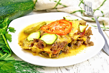 Casserole from minced meat and zucchini in plate on light board