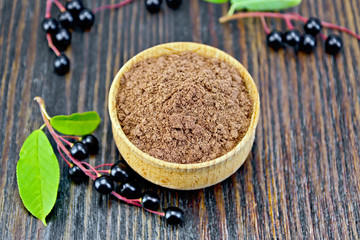 Flour bird cherry in bowl with berries on dark board