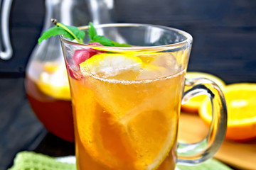 Lemonade with cherries in wineglass and jug on table