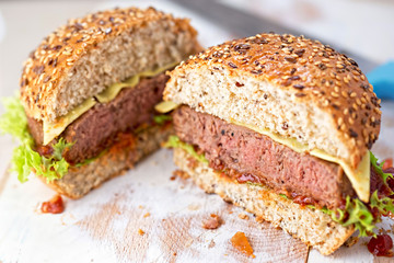 Cut in half angus burger on grain bun with tomato relish, lettuce and cheddar