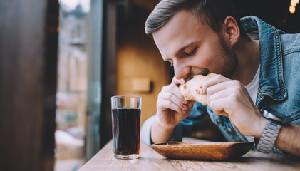 Young man sitting in a restaurant and eating a hamburger