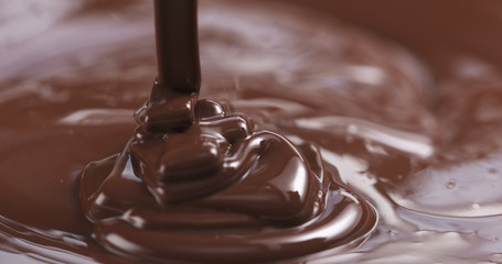 Slow motion of premium dark melted chocolate being poured from spoon in left part of frame, 4k photo