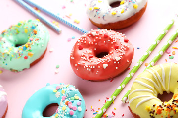 Tasty donuts with sprinkles and tubules on paper background