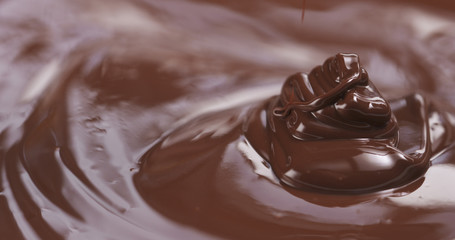 Slow motion of premium dark melted chocolate being poured from spoon in right part of frame, 4k photo