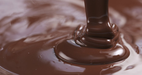 Slow motion of premium dark melted chocolate being poured from spoon in right part of frame, 4k photo