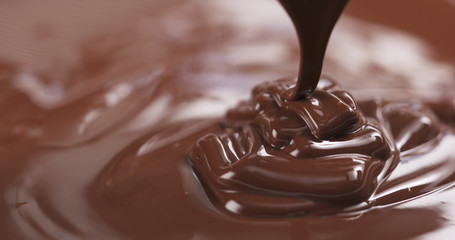 Slow motion of premium dark melted chocolate being poured from spoon in right part of frame, 4k photo