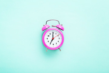 Pink alarm clock on the mint background