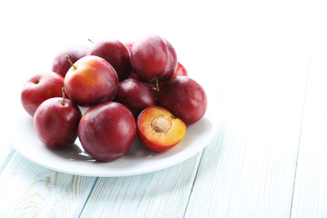 Fresh plums on a white wooden table