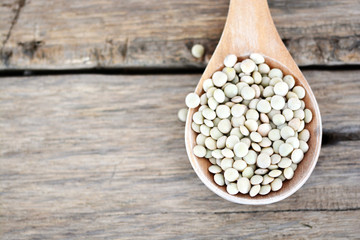 Lentils grains on a spoon on wooden background