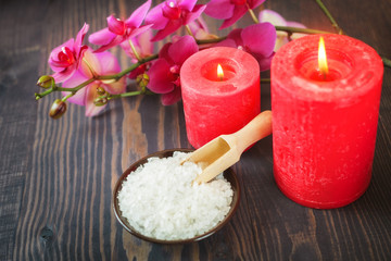 Sea bath salt, candles and flowers on a wooden background. The concept of spa procedures.