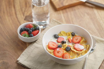 healthy breakfast with corn flakes and berries in white bowl, slightly toned photo