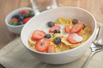 healthy breakfast with corn flakes and berries in white bowl, slightly toned photo