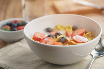 healthy breakfast with corn flakes and berries in white bowl, slightly toned photo