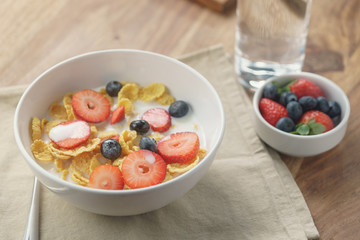 healthy breakfast with corn flakes and berries in white bowl, slightly toned photo