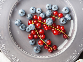 Fresh summer wild blueberries and red currants berries on rustic plate