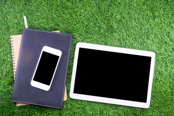 Education concept, Mobile phone with equipment and supplies for work on grass background.