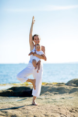 A mother and a son are doing yoga exercises at the seashore of Mediterranean sea
