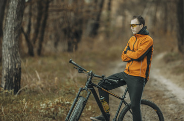 Young attractive man yellow suit on bike on the forest springroad