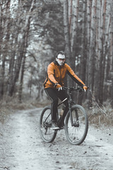 Young attractive man wears yellow suit ride the bike on the forest road