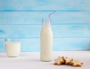 Milk in a glass bottle with a cookie in the form of a star. In the background a glass with yogurt on a blue background. Vegetarian breakfast. Diet.