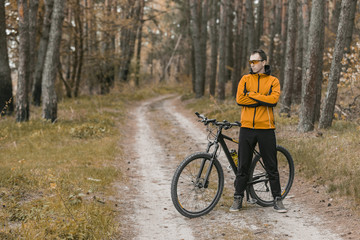 Naklejka premium Young attractive man wears yellow suit on bike in the forest
