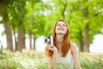 Fototapeta premium portrait of beautiful young woman holding retro camera on the wonderful park background