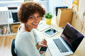 Happy female blogger sitting at desk with laptop