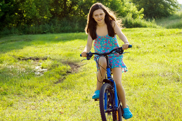 A teenage girl is riding a bicycle on the lawn.