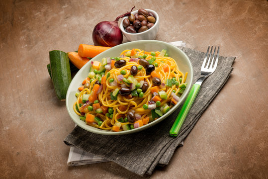 spaghetti with saffron peas black olives and sliced vegetables