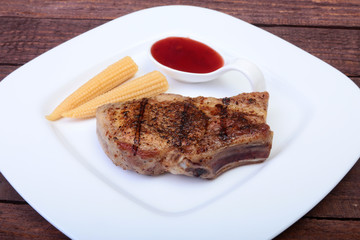 grilled pork chop with Cranberry sauce and Mini Corn cob preserved on plate on wooden board