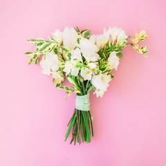 Wedding bouquet of white flowers on pink background. Flat lay, top view. Wedding floristic.