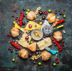 Fototapeta na wymiar Cheese platte with buns, fruits and berries on dark rustic background, top view