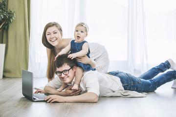 Family mom, dad, and daughter with a laptop together at home happy