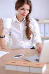 Young businesswoman sitting on the desk with with cup