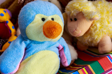Penguin doll beside teddy sheep and other stuffed toys
