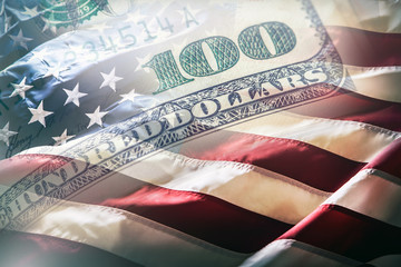 USA flag and American dollars. American flag blowing in the  wind and 100 dollars banknotes in the...