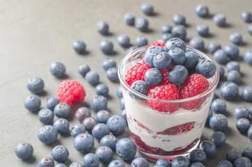 Homemade yogurt with raspberries and blueberries on a gray background. Closeup, copy space