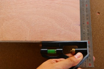 Hand of carpenter is measuring angle of wooden furniture
