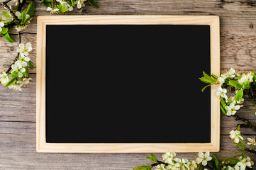 Copy space on a black blackboard with beautiful branches of flowering plum at the corners of the board.