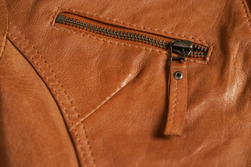 Brown textured leather jacket zippers. Leather jacket macro details. Jacket zippers and pockets